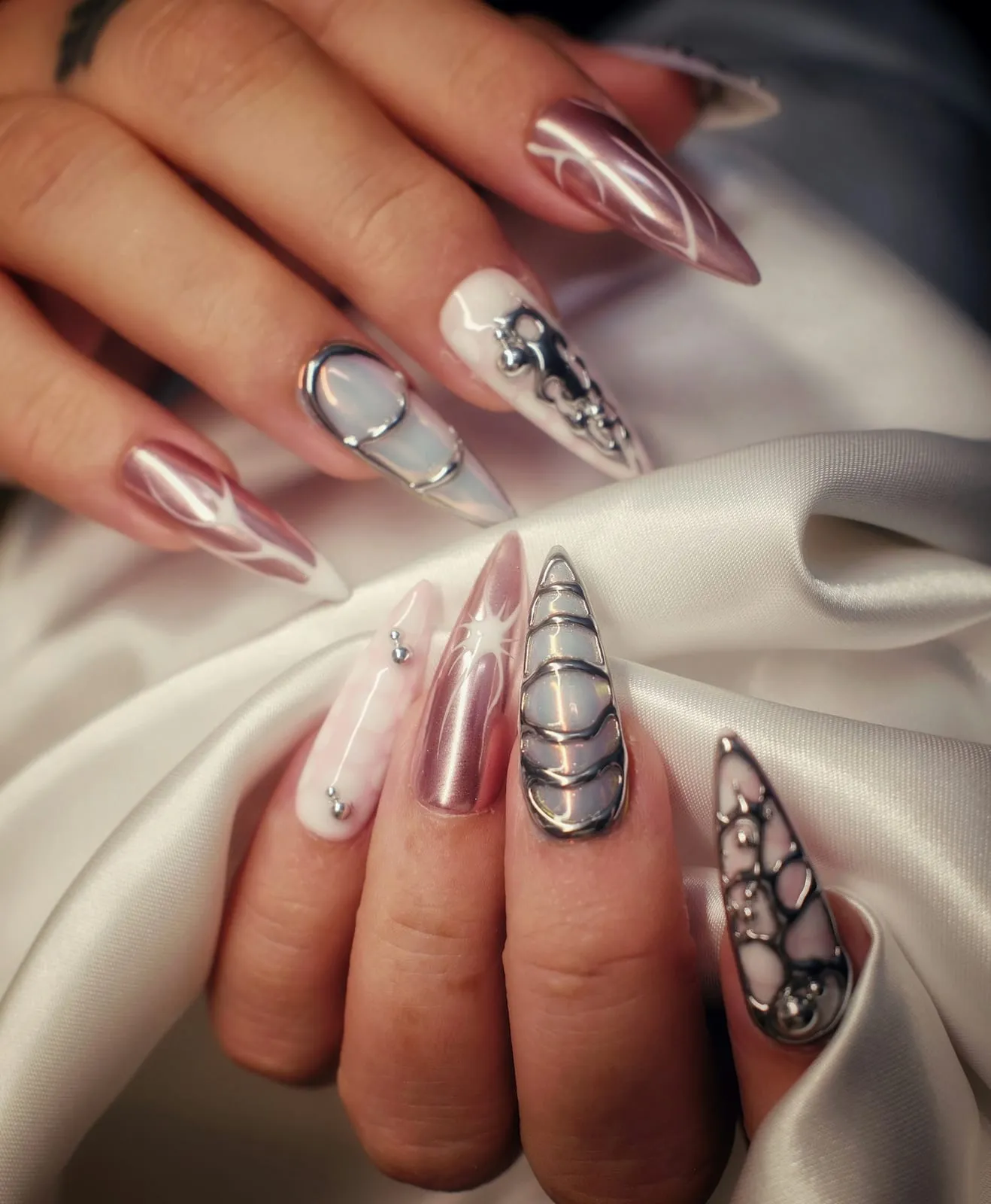 Long stiletto nail extensions with chrome, jewelled and patterned designs